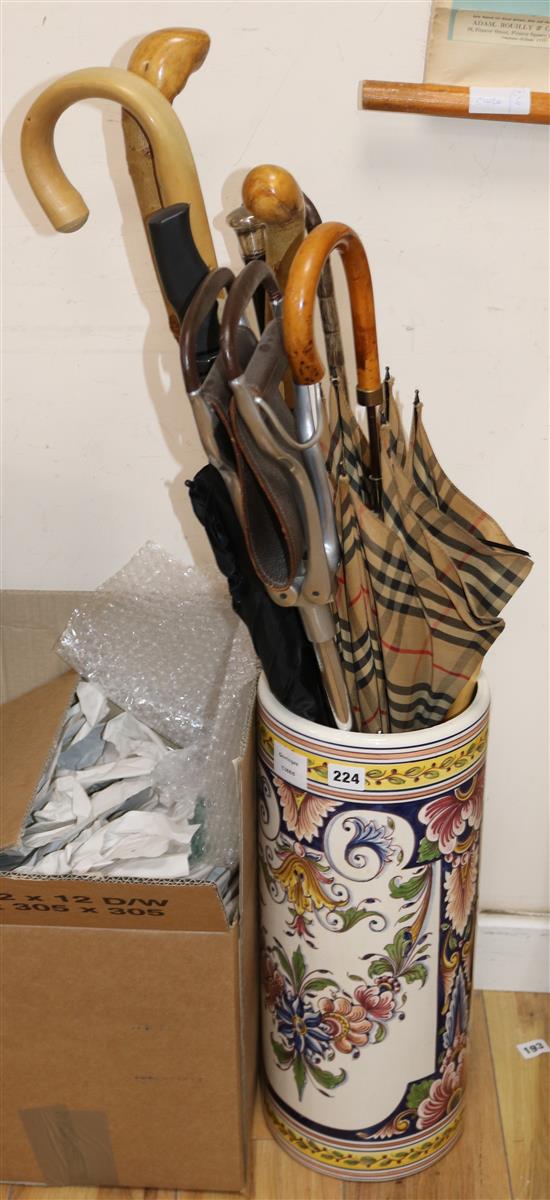 A pottery umbrella stand, with sticks and umbrellas